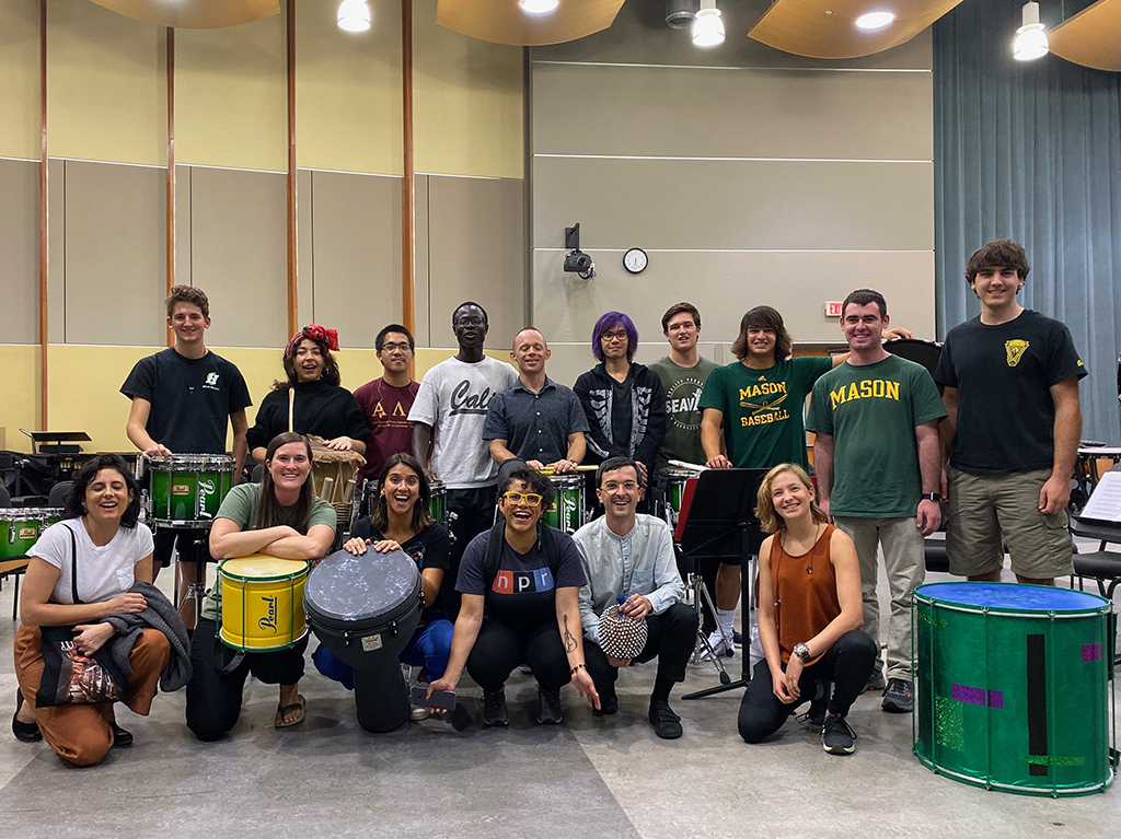 Spirit drumline students and Shane Nickels stand with guest artists in the Performing Arts Building room 3001 for a group photo with their drums.