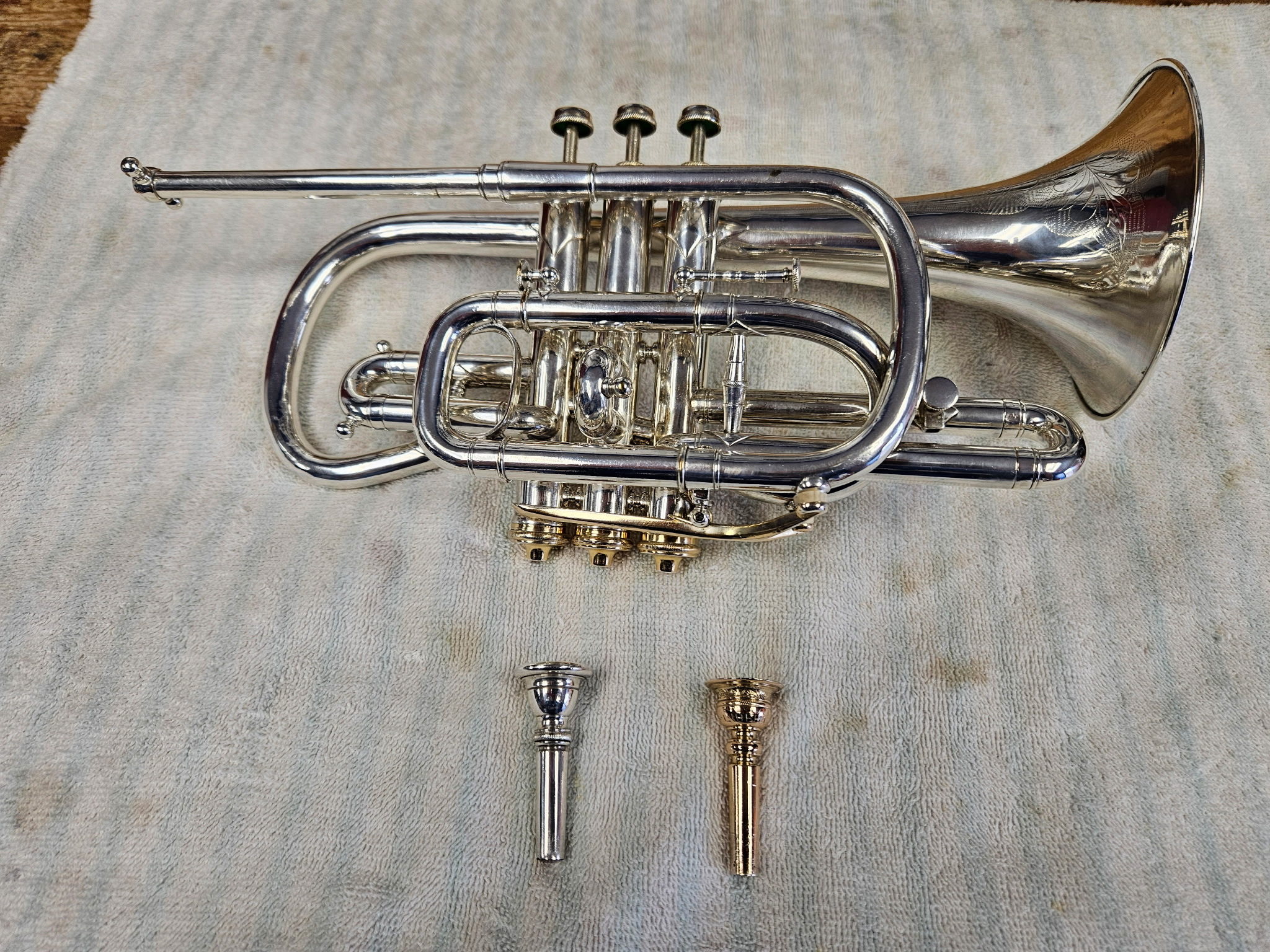 A silver plated cornet with piston valves with two brass mouthpieces