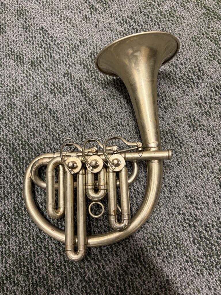 An unmarked by cornet with a unique bell-up design. It features top action rotary valves and is in silver.