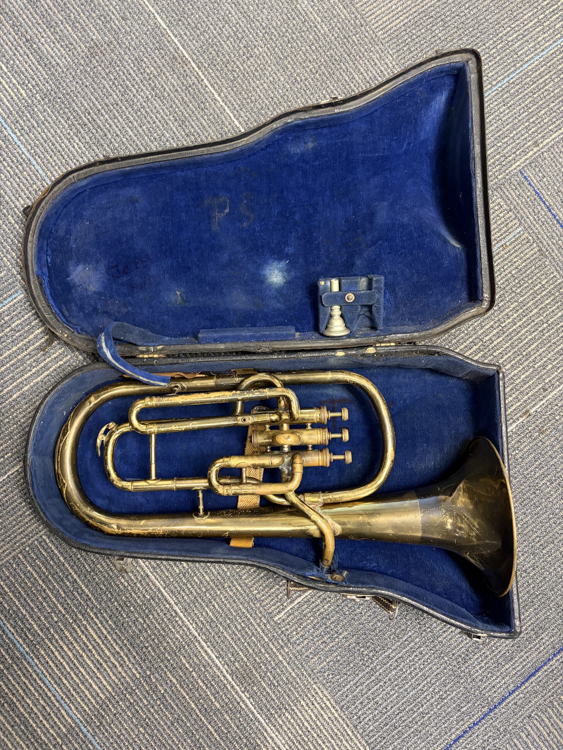 A brass Eb alto horn with three piston valves and German silver mouthpiece resting in a hard case with blue lining
