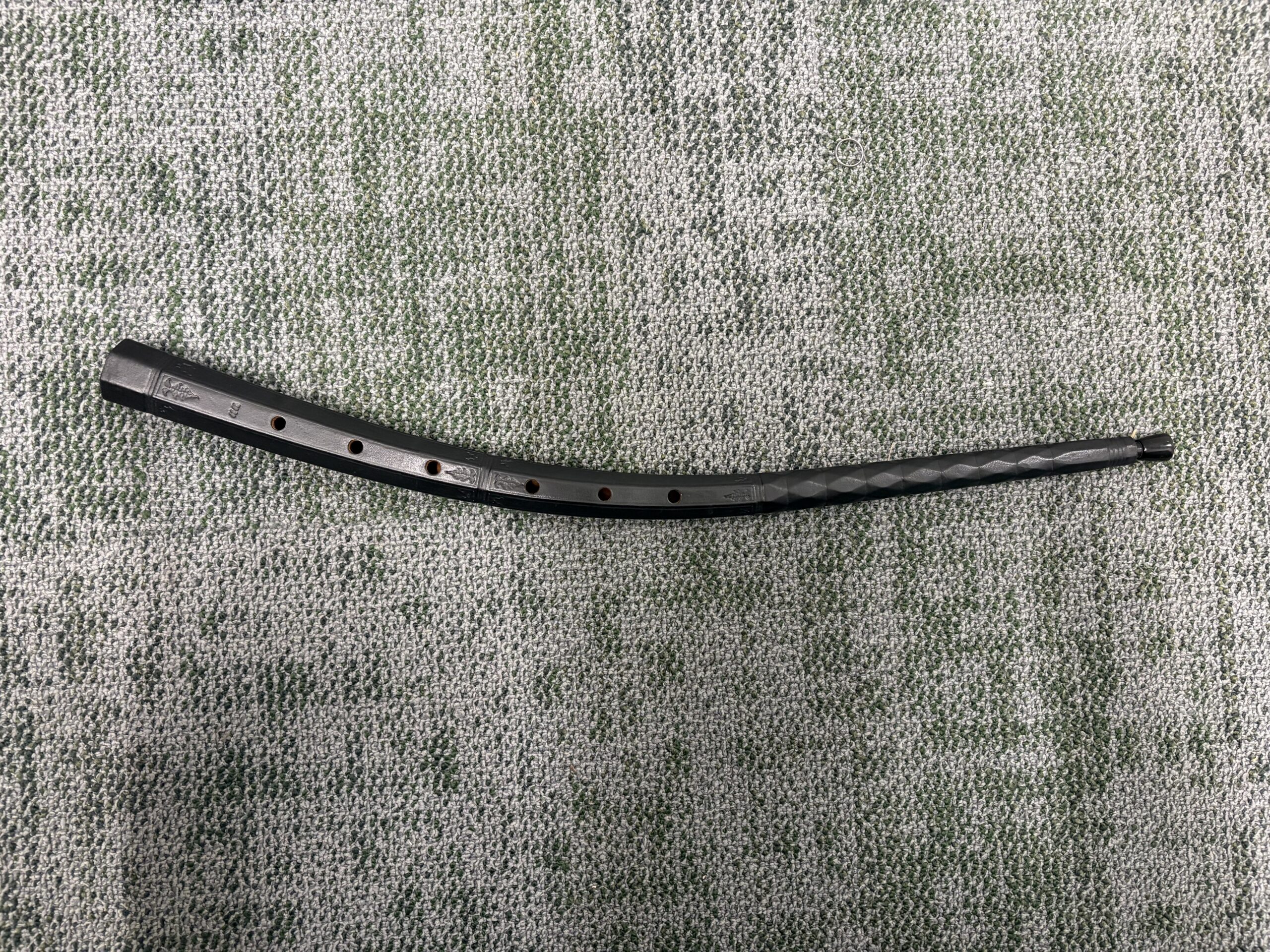 A 6-hole cornetto wrapped in black leather with ornate engravings around the instrument