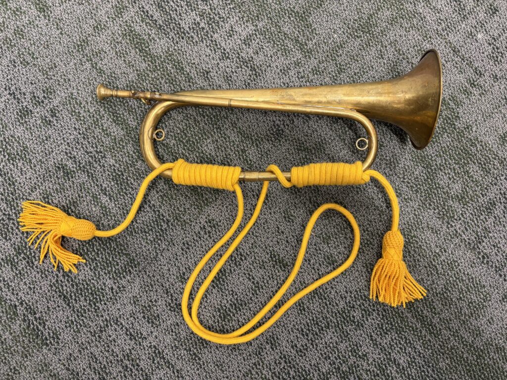 A bugle with gold cord wrapped around the bottom bow with gold tassles