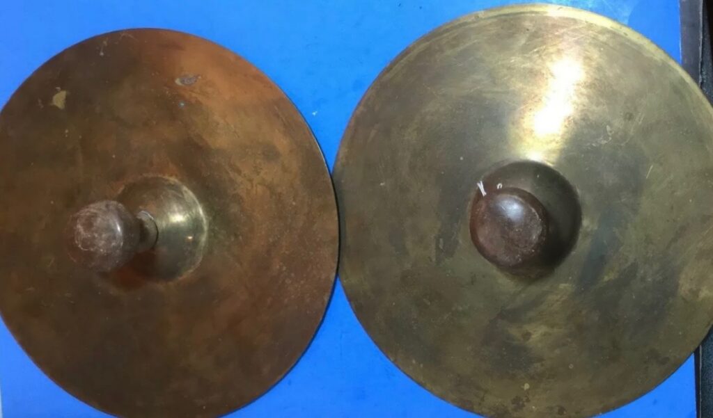 Metal cymbals approximately 9 inches in diameter with wooden knobs for handles